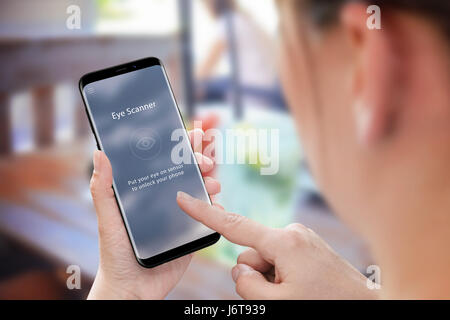 Biometric security with eye scanner app on mobile phone. Modern mobile in woman hand. Stock Photo