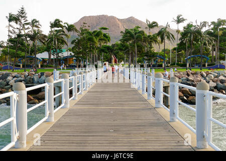 Families walking on the jetty on The Strand in Townsville, Australia with iconic Castle Hill and The Strand Park in the background Stock Photo