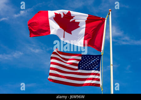 Large Canadian Flag Above Smaller American Flag In The Wind Stock Photo