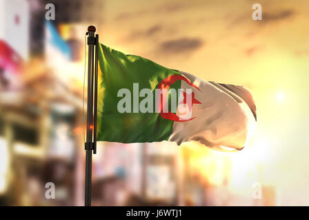 Algeria Flag Against City Blurred Background At Sunrise Backlight Stock Photo