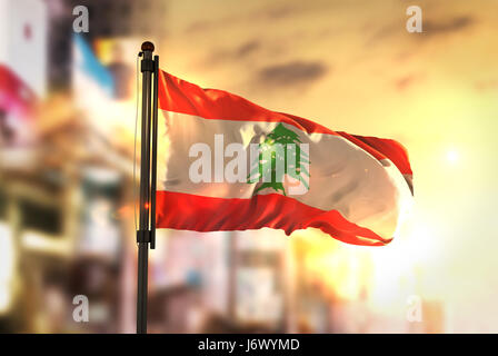 Lebanon Flag Against City Blurred Background At Sunrise Backlight Stock Photo