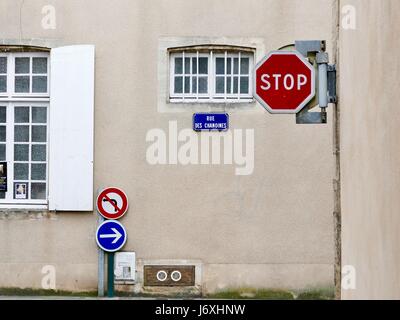 Signs of Bayeux - Stop, No left turn, Go right - against a stone building with white wood framed windows. Bayeux, Calvados, France Stock Photo