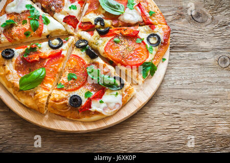 Italian Pizza with Tomatoes, Salami, black Olives and Mozzarella Cheese close up. Fresh Homemade Pizza. Stock Photo