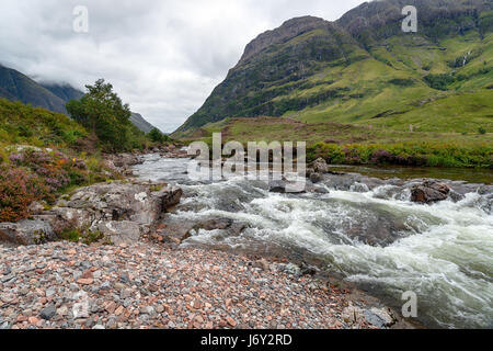 The river Coe flowing through the valley below mountains at Glencoe in the Scottish Highlands Stock Photo