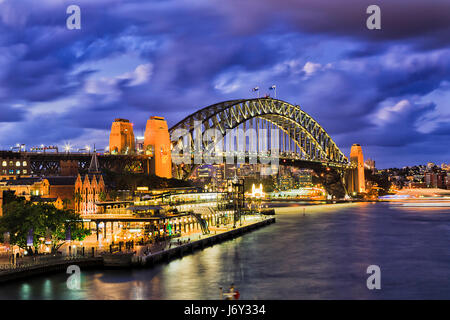 Huge illuminated arch of Sydney Harbour bridge connecting city CBD from the Rocks to North Sydney. Bright lights reflect in blurred waters of Sydney H Stock Photo