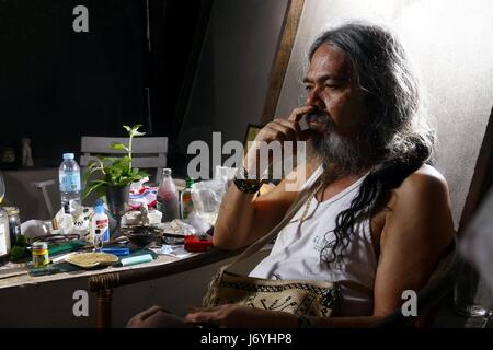 QUEZON CITY, PHILIPPINES - FEBRUARY 3, 2017: A sculptor sits in his workshop or studio and contemplate on his next art project Stock Photo