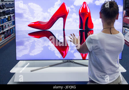 Woman looking at Samsung QLED TV in electrical store.