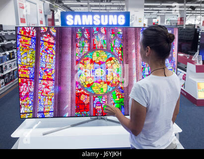 Woman looking at Samsung QLED TV in electrical store.