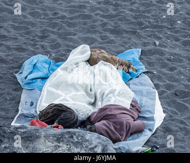 Hippies and dog sleeping on beach Stock Photo