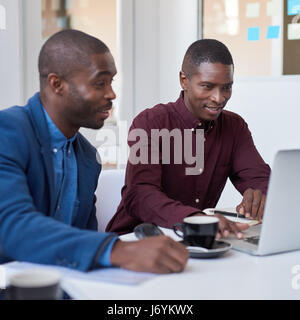 African businessmen working on a laptop in an white office Stock Photo