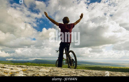 man on bicycle with covered by forest hills Stock Photo