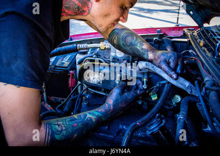 Man with tattoos working on car engine Stock Photo