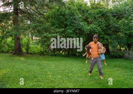 Father playing with two children in the garden Stock Photo