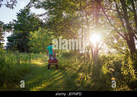 Father pulling three children in a wagon Stock Photo