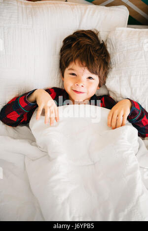 Portrait of a smiling boy lying in bed Stock Photo