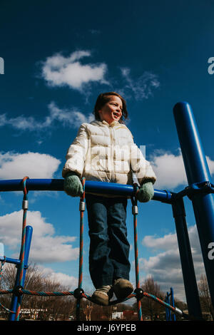 Girl standing on climbing frame in playground Stock Photo