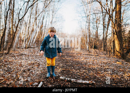 Boy standing in forest pulling funny faces Stock Photo