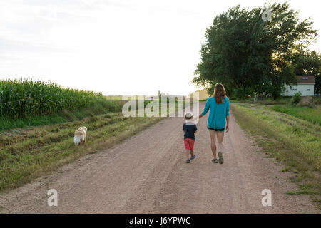 Mother and son walking down the road with a golden retriever dog Stock Photo