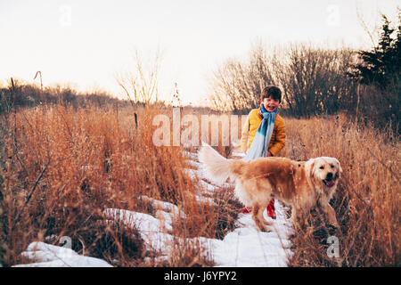 boy walking through rural landscape with golden retriever dog Stock Photo