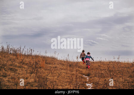 Two children running up a hill Stock Photo
