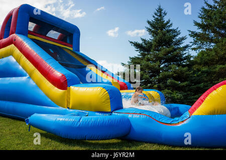 boy playing on inflatable water slide Stock Photo