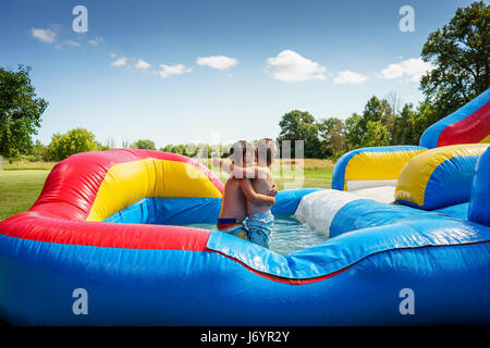 Two boys hugging on an inflatable water slide