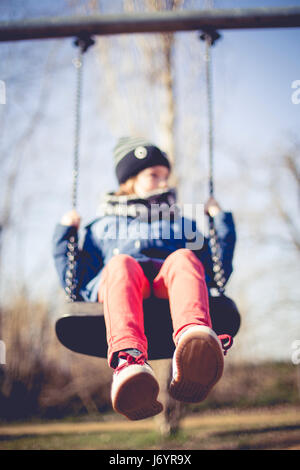 Boy sitting on a swing in the park Stock Photo