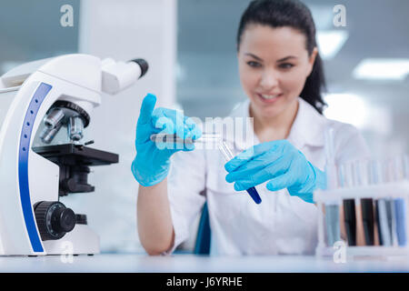 Positive delighted female scientist adding powder to reagent Stock Photo