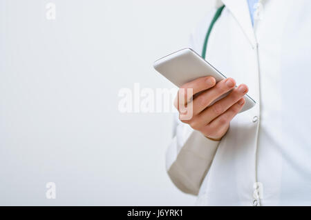 A female doctor texting on smartphone in medical office Stock Photo