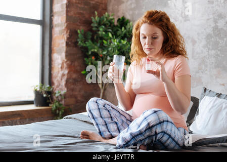 Mature pregnant women taking medicine with water Stock Photo