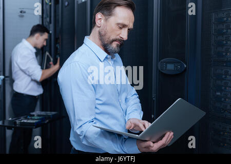 Serious experienced programmer holding a laptop Stock Photo