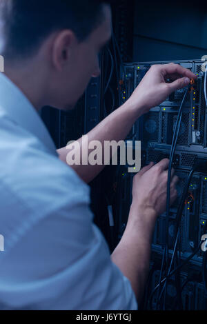 Nice male technician connecting the cable to the data server Stock Photo