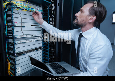 Serious bearded technician checking the wire connection Stock Photo