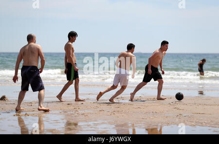 People play football as they enjoy the warm weather on Bournemouth beach in Dorset as forecasters predict that a wave of warm air will move across the country in the coming days. Stock Photo