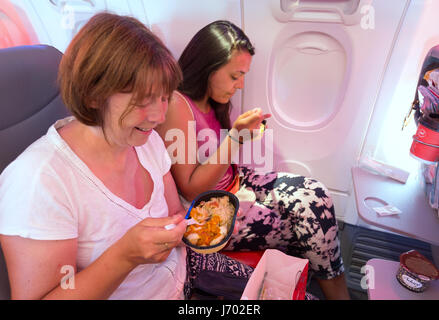 Airplane meal: Two women airplane passengers eating airline food on a Jet2 flight, from Lanzarote to the UK