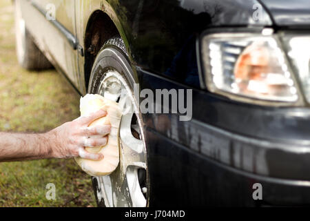 A man washes a car sponge with an aluminum alloy car shampoo. Stock Photo