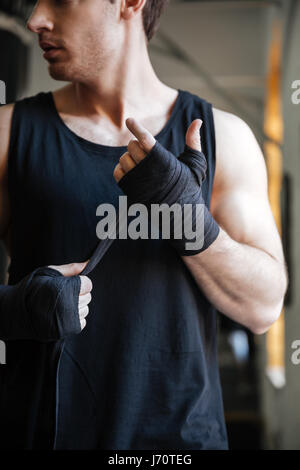 Cropped image of strong man wearing black gloves for boxing in gym Stock Photo
