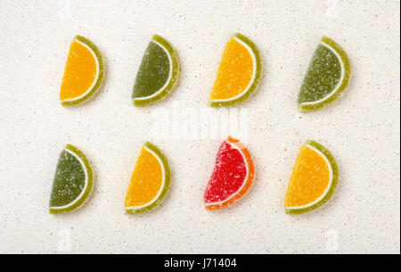 Colored marmalade sweets in the form of citrus fruits are laid out in a pattern 2 rows on a gray table top Stock Photo