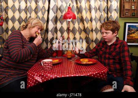 Mother and son having lunch while looking at their smart phones Stock Photo