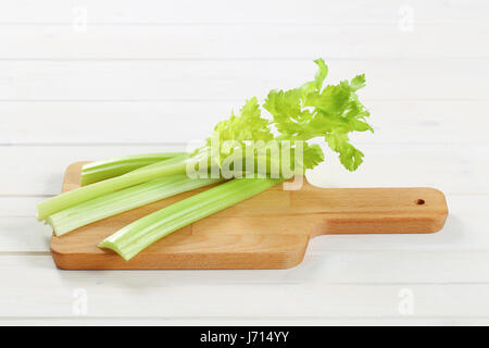 stems of green celery on wooden cutting board Stock Photo
