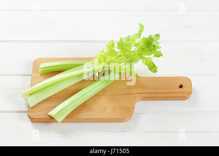 stems of green celery on wooden cutting board Stock Photo