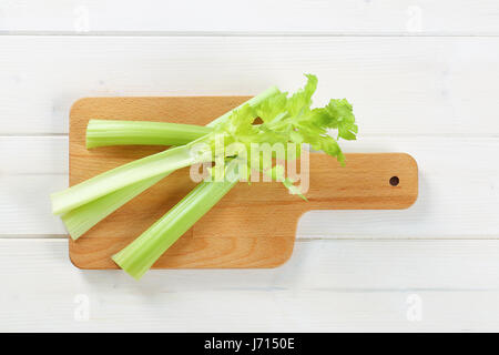 stems of green celery on wooden cutting board Stock Photo