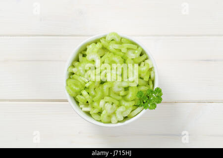 bowl of chopped celery stems on white wooden background Stock Photo