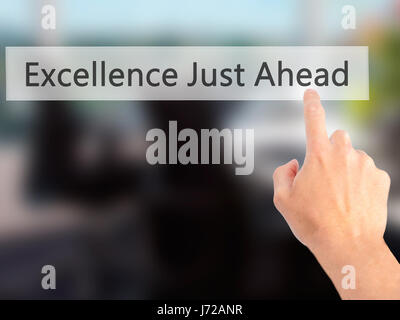 Excellence Just Ahead - Hand pressing a button on blurred background concept . Business, technology, internet concept. Stock Photo Stock Photo