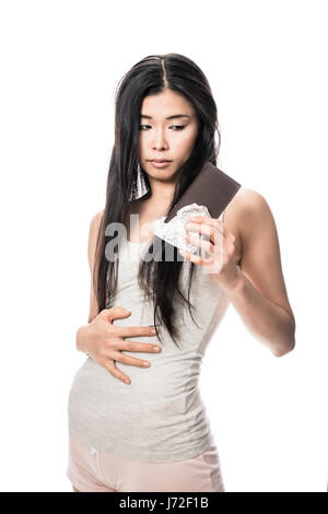 Woman touching her abdomen while looking at chocolate Stock Photo