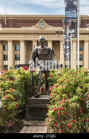 Wellington, New Zealand - March 10, 2017: Classic iconic Mahatma Gandhi bronze statue in front of yellow central railway station with clock. Green bus Stock Photo