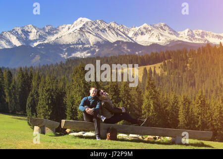 Young couple on mountain background. Beautiful smiling couple in mountain nature. Young happy people on a sunny day. Stock Photo