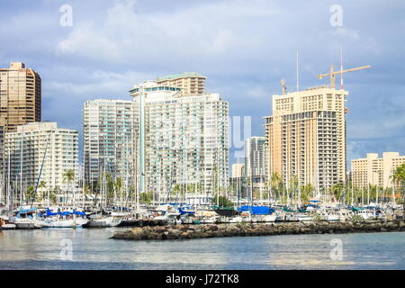 Honolulu, Hawaii, USA - May 30, 2016: Yachts docked at Ala Wai Boat Harbor in the Kahanamoku Lagoon against cityscape of Ala Moana. Stock Photo