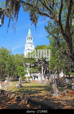 Spire and graveyard framed by Spanish moss-covered trees at the parish church of St. Helena in the historic district of downtown Beaufort, South Carol Stock Photo