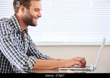 profile image of handsome groomed man typing on laptop computer Stock Photo